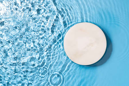 Transparent and clean blue water background with podium and sunlight reflectionの写真素材