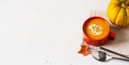 Autumn pumpkin soup in red or orange bowl with vegetablesの写真素材