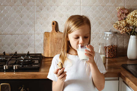 Little girl have a snack with nuts bar and milkの写真素材