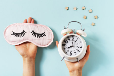 Sleep concept with mask and alarm on blue background, top view, flat lay, copy space