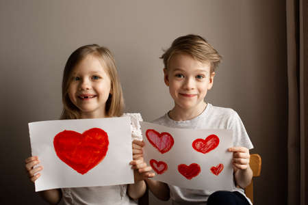 Kids painting red valetine heart card on table at home