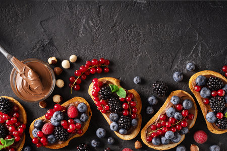 Bread toast with chocolate paste and berries on black background, top view. copy space