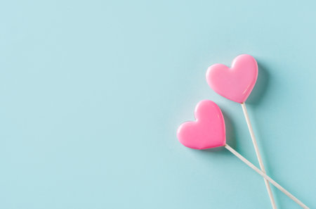 Candy pink lollipops on blue background, valentines day concept, card, copy space, top viewの写真素材