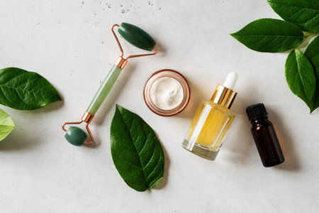Spa and face care concept with serum, massage roll and green leaves on white background, top view, copy spaceの写真素材