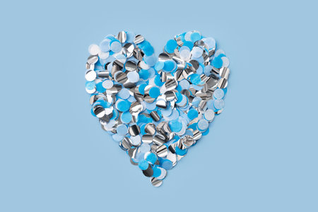 Confetti paper heart shape, blue white and sparkle on blue background,