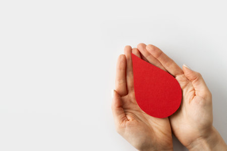 World donor day concept with hands holding paper red drop on white background, top view. copy spaceの写真素材