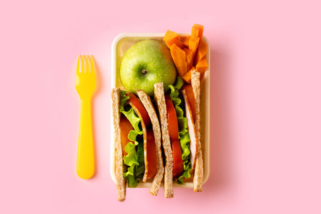Sandwich toast with fresh salad, tomato, bacon in lunch box on pink background, copy spaceの写真素材