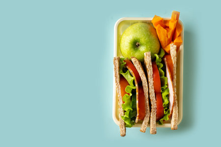Sandwich toast with fresh salad, tomato, bacon in lunch box on blue background, copy spaceの写真素材
