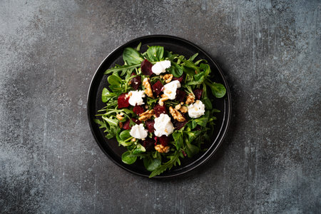 Fresh salad with beetroot, arugula and cheese on black plate on dark background, close up, top view, copy spaceの写真素材