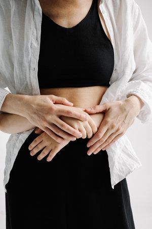 Kids hands hugging mothers on belly close-up, concept of support trust love friendship, mothers day, lifestyleの写真素材