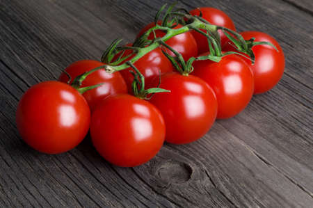 Bunch of ripe delicious red cherry tomatoes close-up on wooden backgroundの写真素材