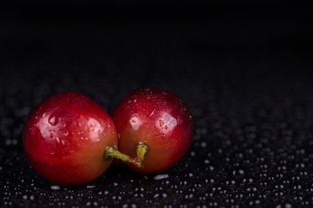 Juicy red grapes on a black background in drops of water.の写真素材