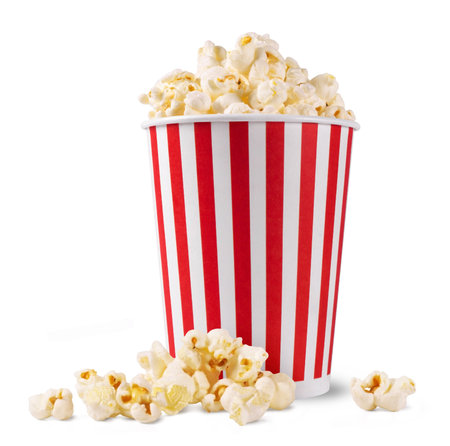 Popcorn in a striped bucket and a handful of popcorn flakes isolated on a white background.の写真素材