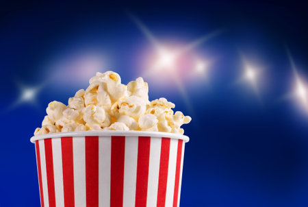 Bucket with popcorn on a blue background with lightsの写真素材
