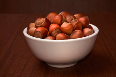 A nut in a white bowl against the background of a dark tree. Side view.の写真素材