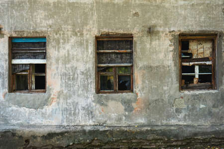 The old dirty broken window on the old dirty wall with cracks.の写真素材