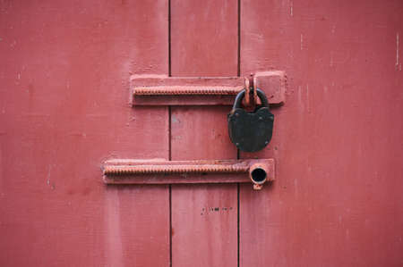 The metal door is red with a padlock. Close-up.の写真素材