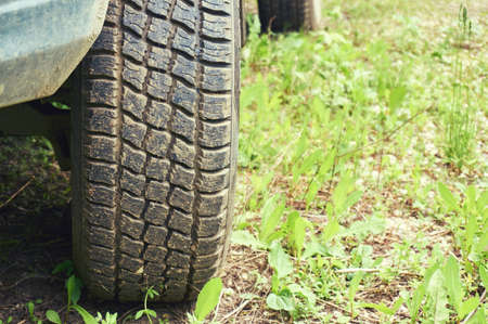 The wheel of the car close-up on a background of green grass. Abstract background.