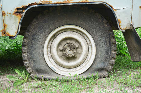 Flat tire on an old rusty SUV close-up. Abstract background.の写真素材