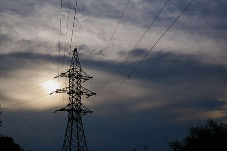 A line of high-voltage cables against a gray sky with clouds. Abstract background.