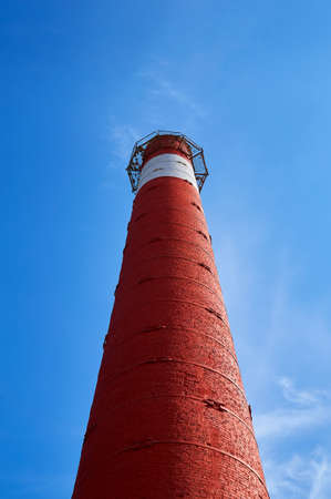 A large red brick pipe from the boiler room against the blue sky. Industrial background.の写真素材