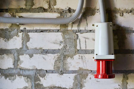 Red Industrial Appliance Connector located on a brick wall.の写真素材