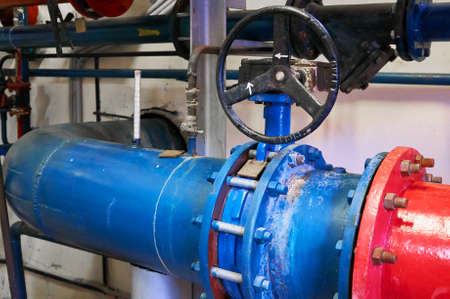 Gate valves installed on pipes painted in blue. Industrial background.