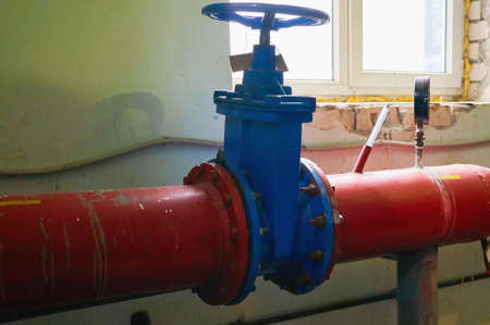 Big blue valve on the pipe painted in red color.