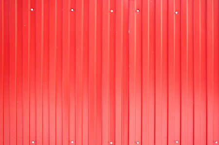 Texture of a metal fence from the profile of a red sheet with vertical lines.の写真素材