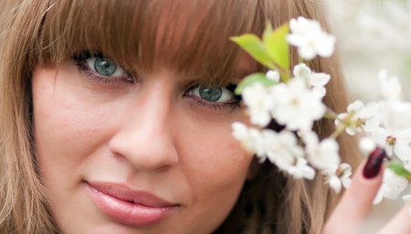 The beautiful girl holds a blossoming branch of a cherryの写真素材