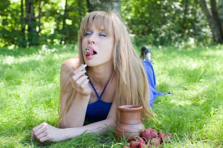 The woman in a grass also enjoys a strawberryの写真素材