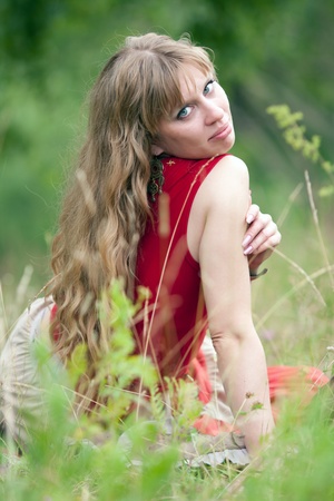 The girl of hippie sits in a green grass  の写真素材