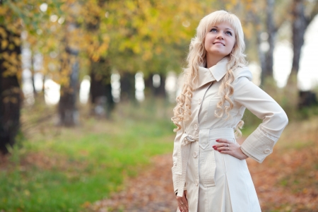 The girl in a raincoat walks in autumn parkの写真素材
