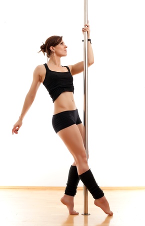 The beautiful young woman dances and keeps for a poleの写真素材