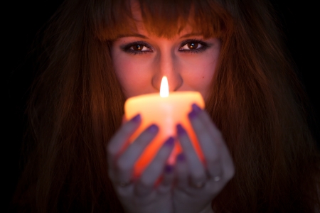 face of a woman witch with red hair and a candleの写真素材