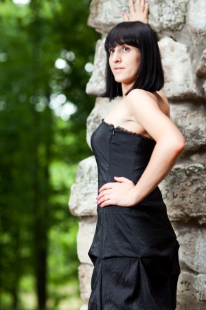 woman in black dress standing near a stone wallの写真素材