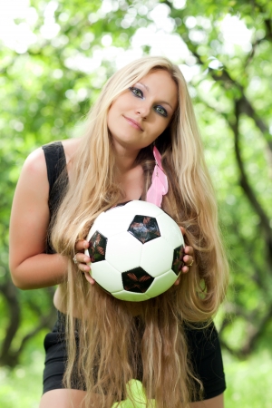 beautiful woman with long hair holding a soccer ball girl standing outdoors and holding a ballの写真素材