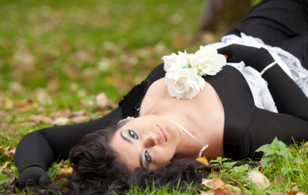 Young beautiful gothic girl lying on the grassの写真素材