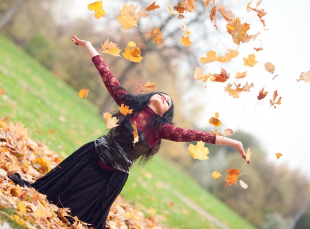 Young beautiful gothic girl sitting on the grass in the autumn leavesの写真素材