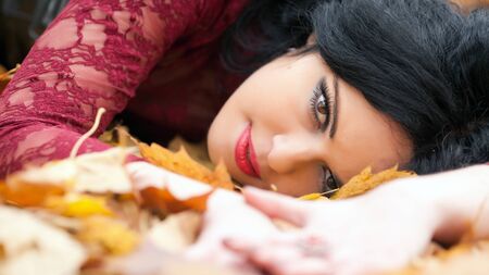 Young beautiful gothic girl lying in autumn leaves
