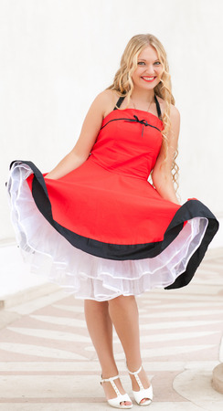 cheerful young woman standing in an old fashioned red dressの写真素材