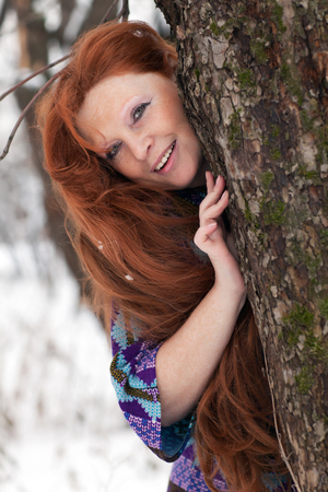 beautiful adult woman with long red hair in winterの写真素材