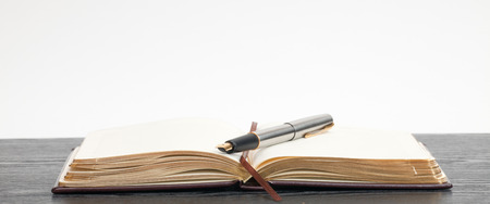 Opened notebook and a pen lying on a wooden tableの写真素材