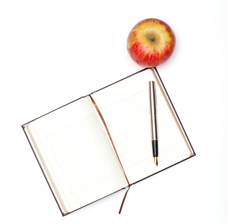 Open notebook and an apple lying on a white backgroundの写真素材