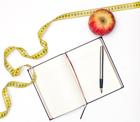 Open notebook and an apple lying on a white backgroundの写真素材