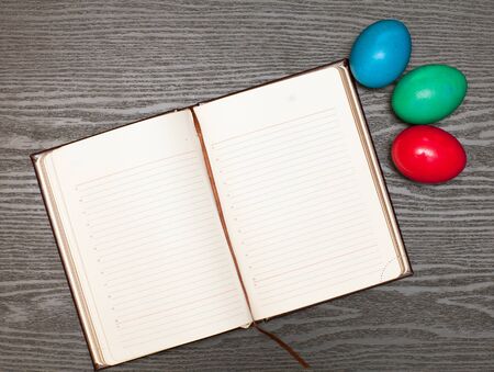 Easter eggs and notebook lying on a wooden tableの写真素材