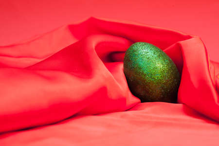 Beautiful easter green egg lies on red clothの写真素材