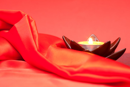 Candle and red satin cloth. Beautiful red backgroundの写真素材