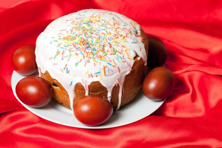 Easter cake and painted eggs on red cloth closeup