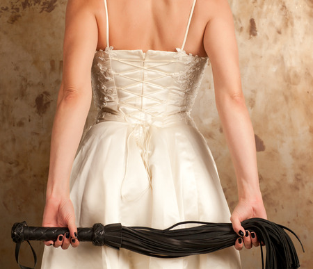 Beautiful woman in white dress holding a whipの写真素材